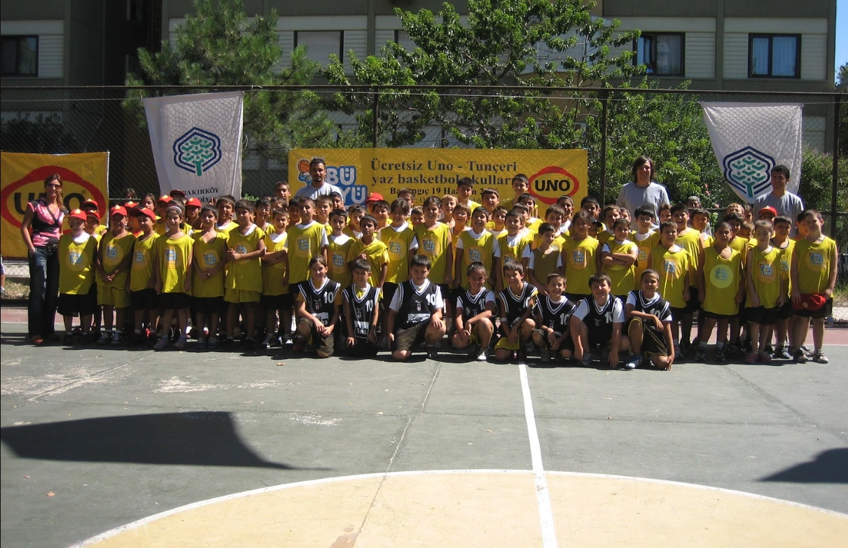 Basketbol sahasında çocuklar ve eğitmenlerle toplu hatıra fotoğrafı