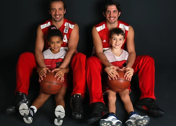 İki sporcu ve iki çocuk, basketbol toplarıyla çekilmiş stüdyo portresinde