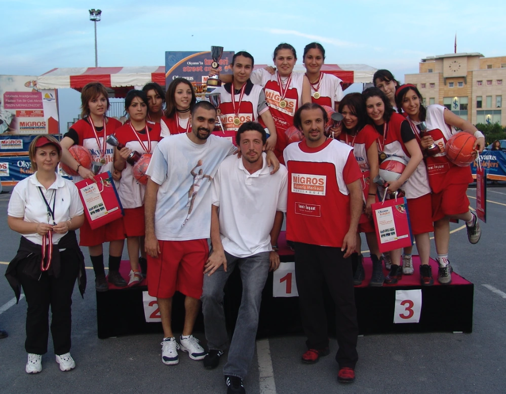 Basketbol takımının kupa ve madalyalarıyla ödül kürsüsünde birlikte poz verdiği grup fotoğrafı