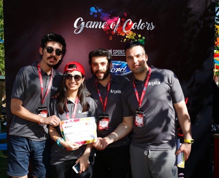 Game of Colors panosu önünde sertifikayla hatıra fotoğrafı çektiren takım