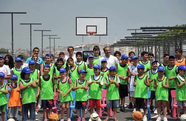 Açık hava basketbol sahasında antrenman yelekleri ve şapkalarıyla bir araya gelen çocuklar — temsili arşiv görseli